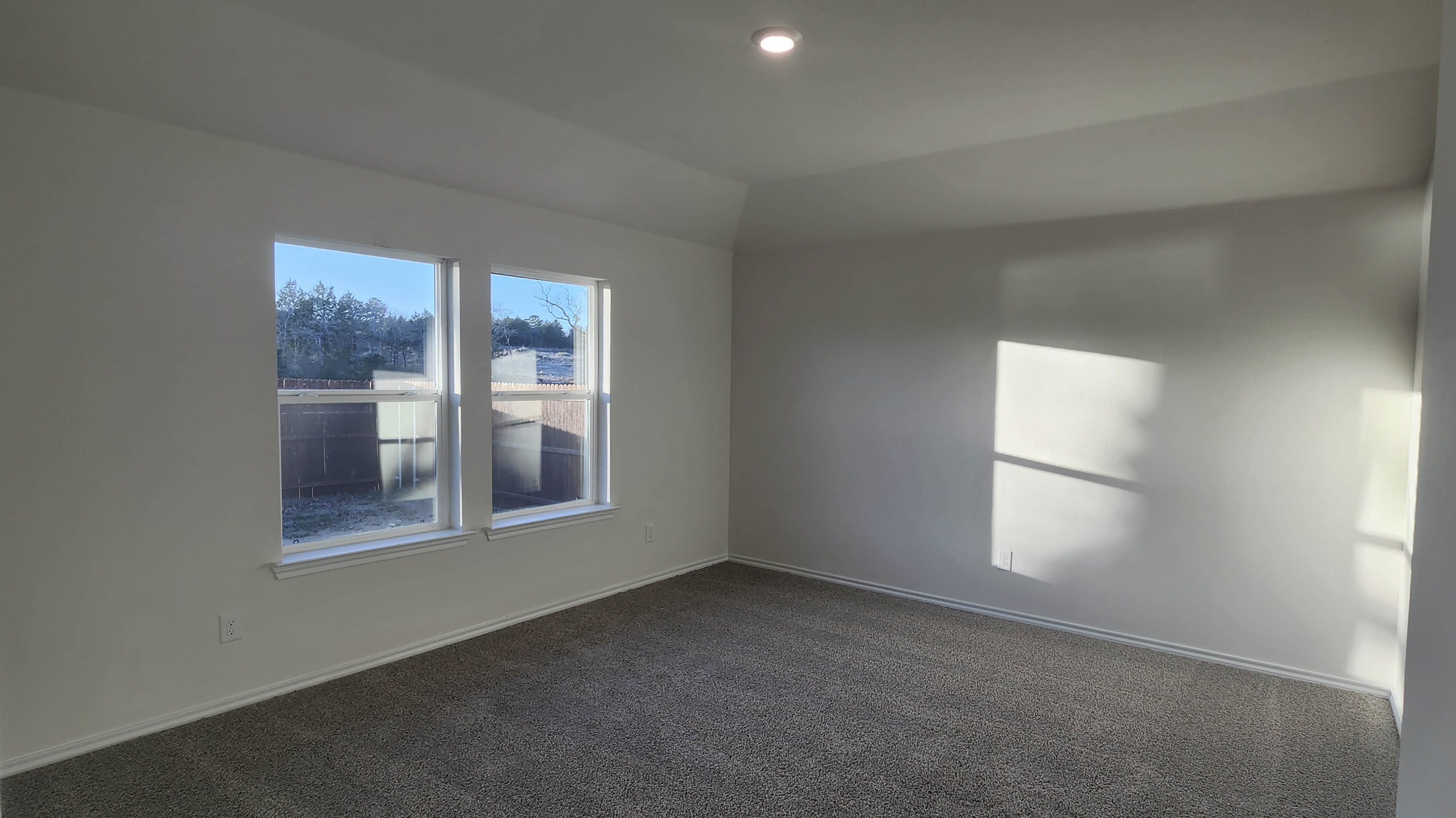 primary bedroom with large windows facing the backyard