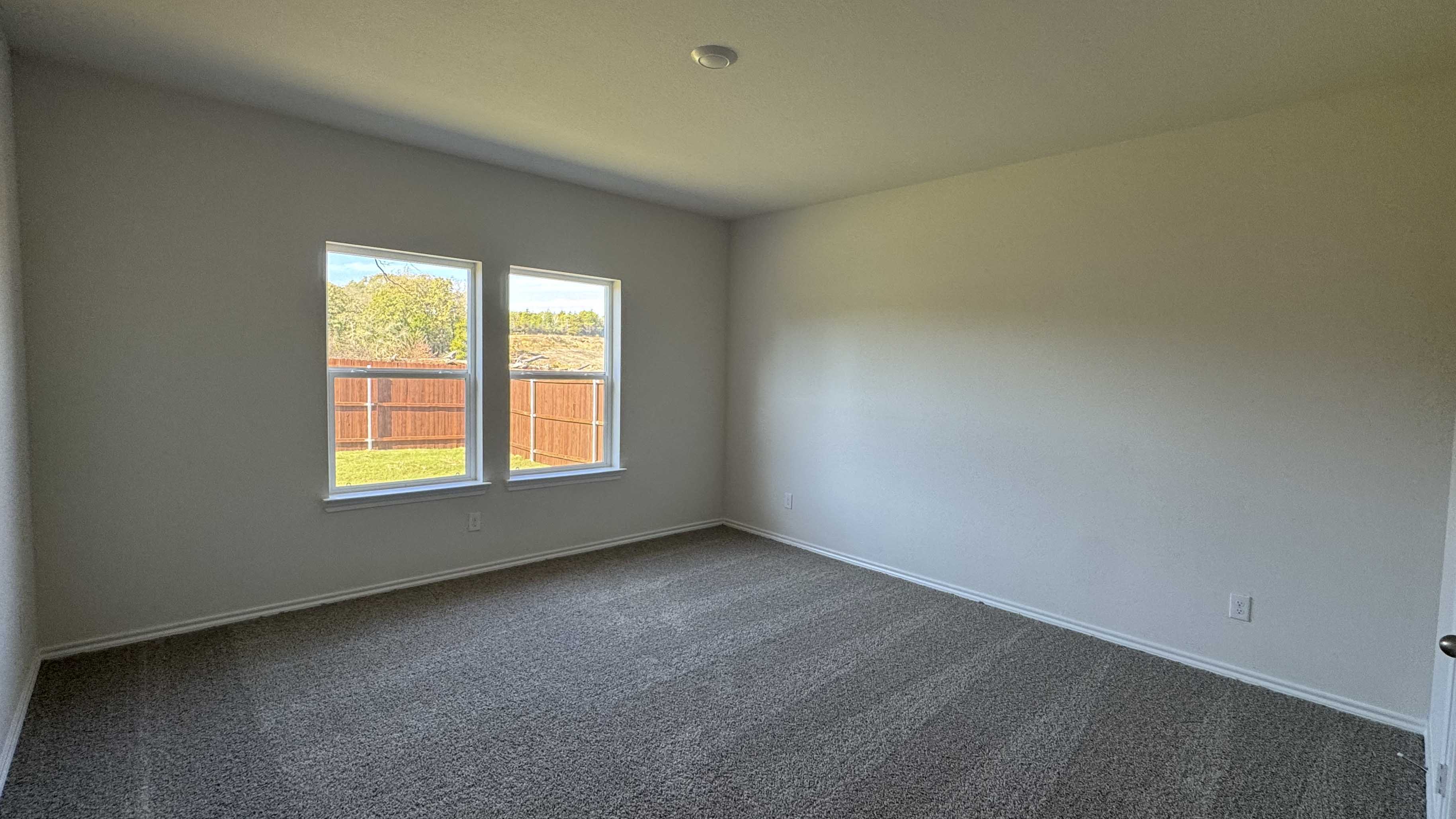 primary bedroom with large windows facing the backyard