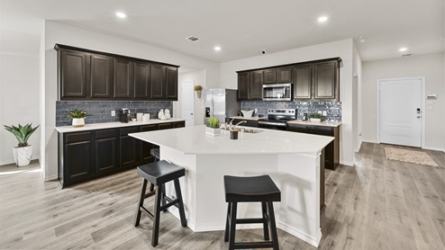 large kitchen with large island and brown cabinets next to front entry