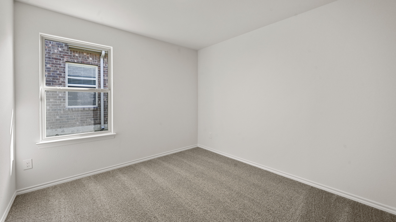 Secondary bedroom with carpet and white walls with large window providing natural light
