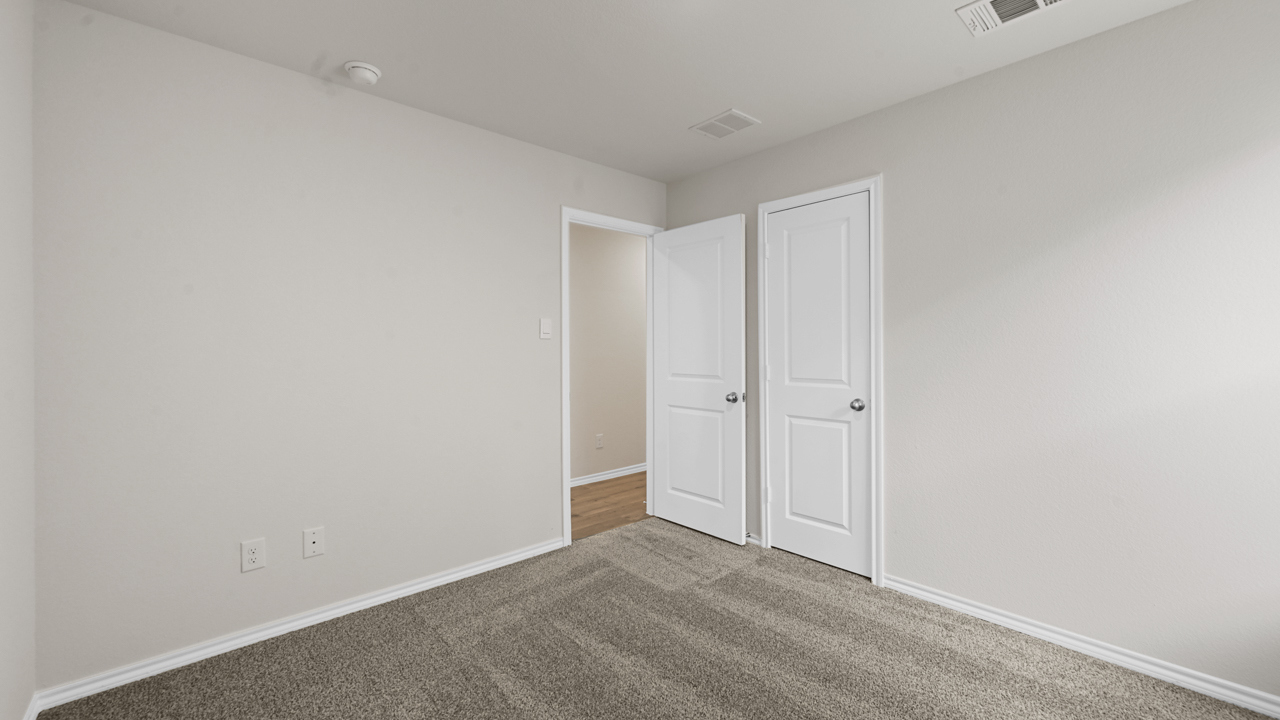 Secondary bedroom with carpet and white walls with large window providing natural light