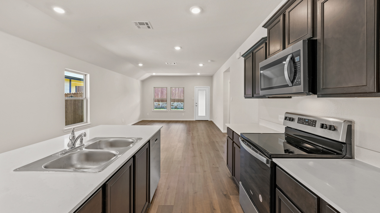 Kitchen area with hardwood floors white counters and dark cabinets with kitchen island