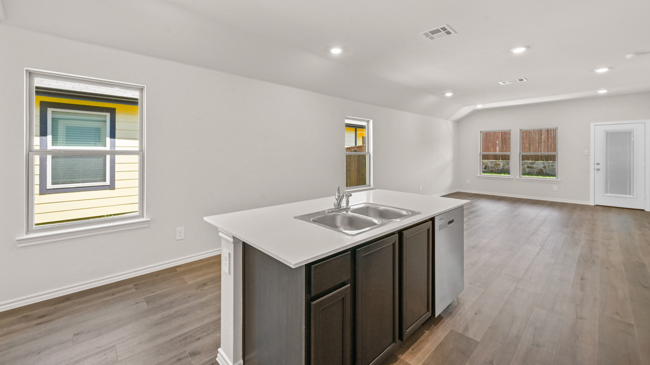 Kitchen area with hardwood floors white counters and dark cabinets with kitchen island