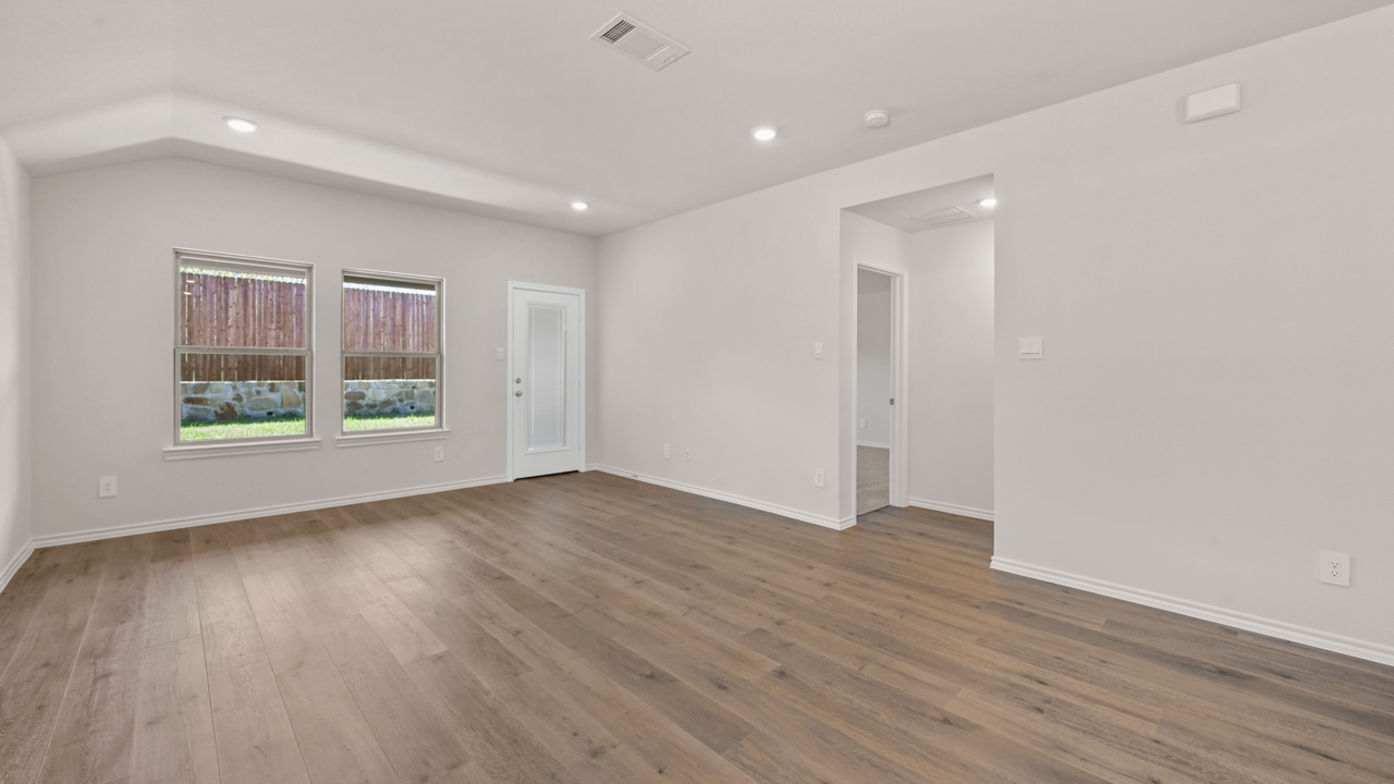 Open concept living area with hardwood floors and large windows facing the backyard providing natural light