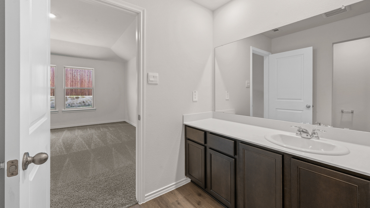 Primary bathroom with hardwood floors dark cabinets and white counters
