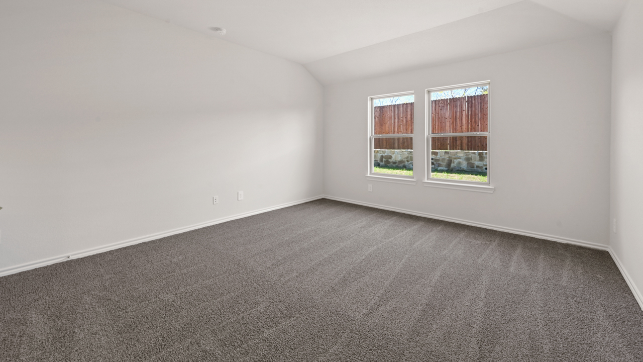 Primary bedroom with light colored carpet white walls and large windows facing the backyard providing natural light