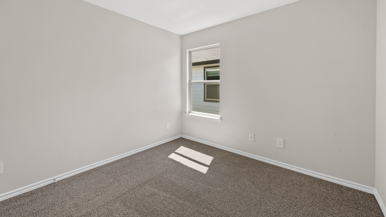 Secondary bedroom with white walls carpet and large window providing natural light
