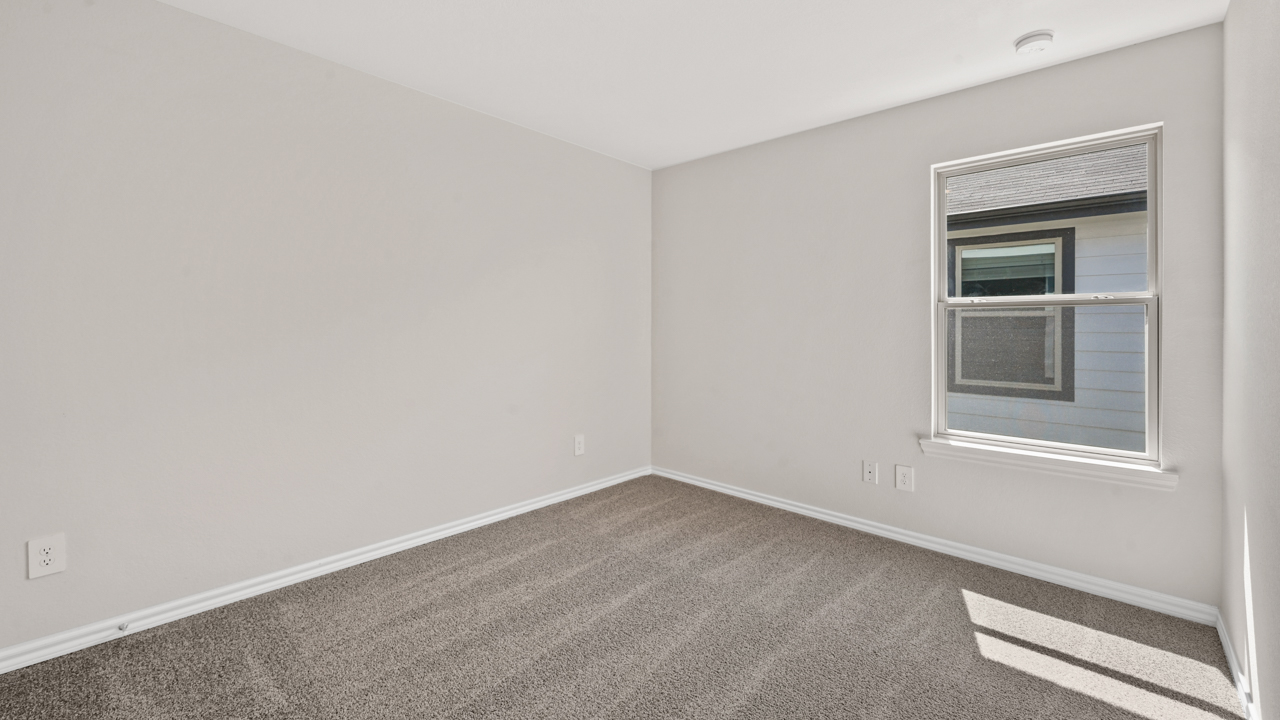 Secondary bedroom with white walls carpet and large window providing natural light