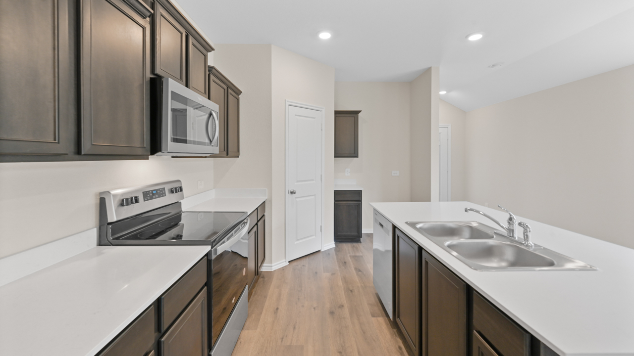 Kitchen area with light colored counters dark cabinets and hardwood floors with kitchen island