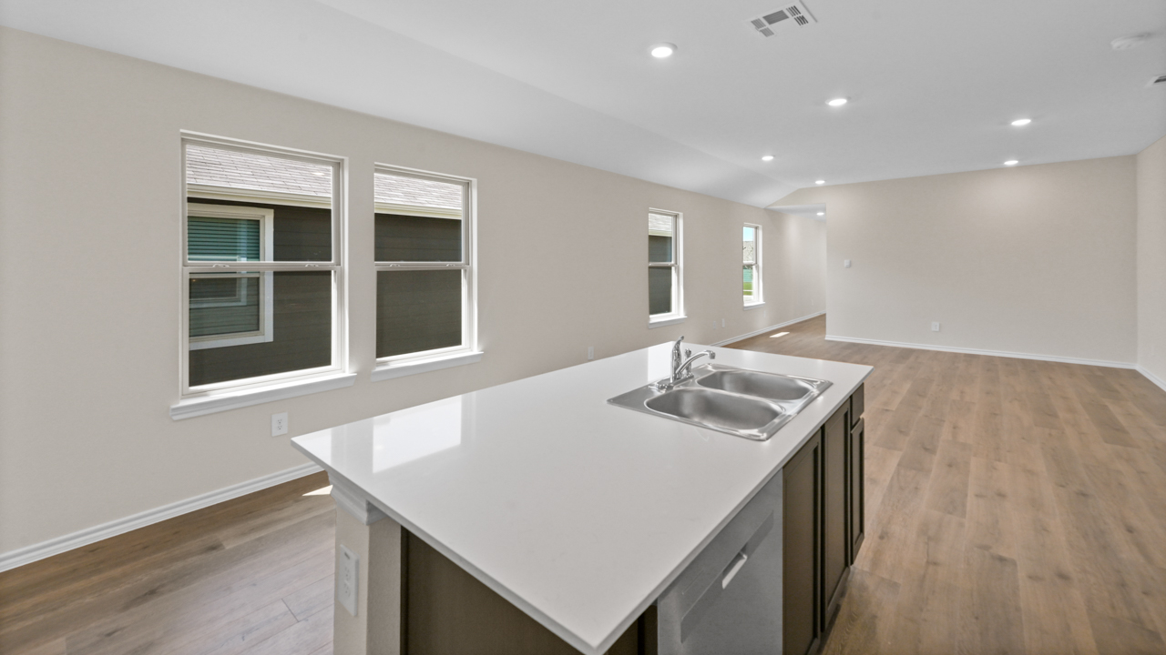 Kitchen area with light colored counters dark cabinets and hardwood floors with kitchen island
