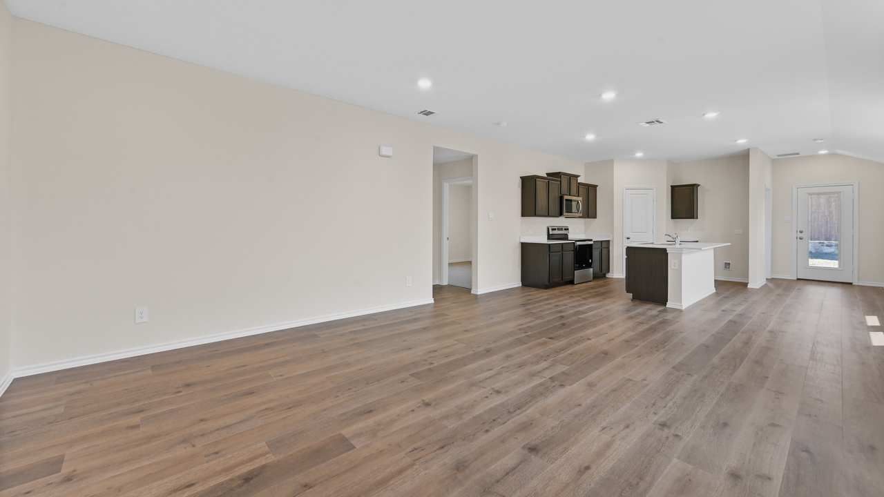 Open concept living area with hardwood floors and large windows facing the backyard providing natural light