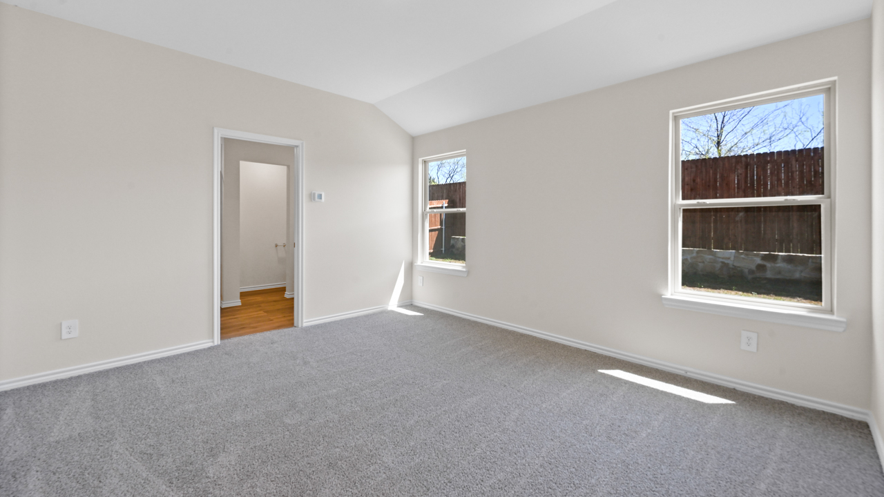 Primary bedroom with light colored carpet white walls and large windows providing natural light