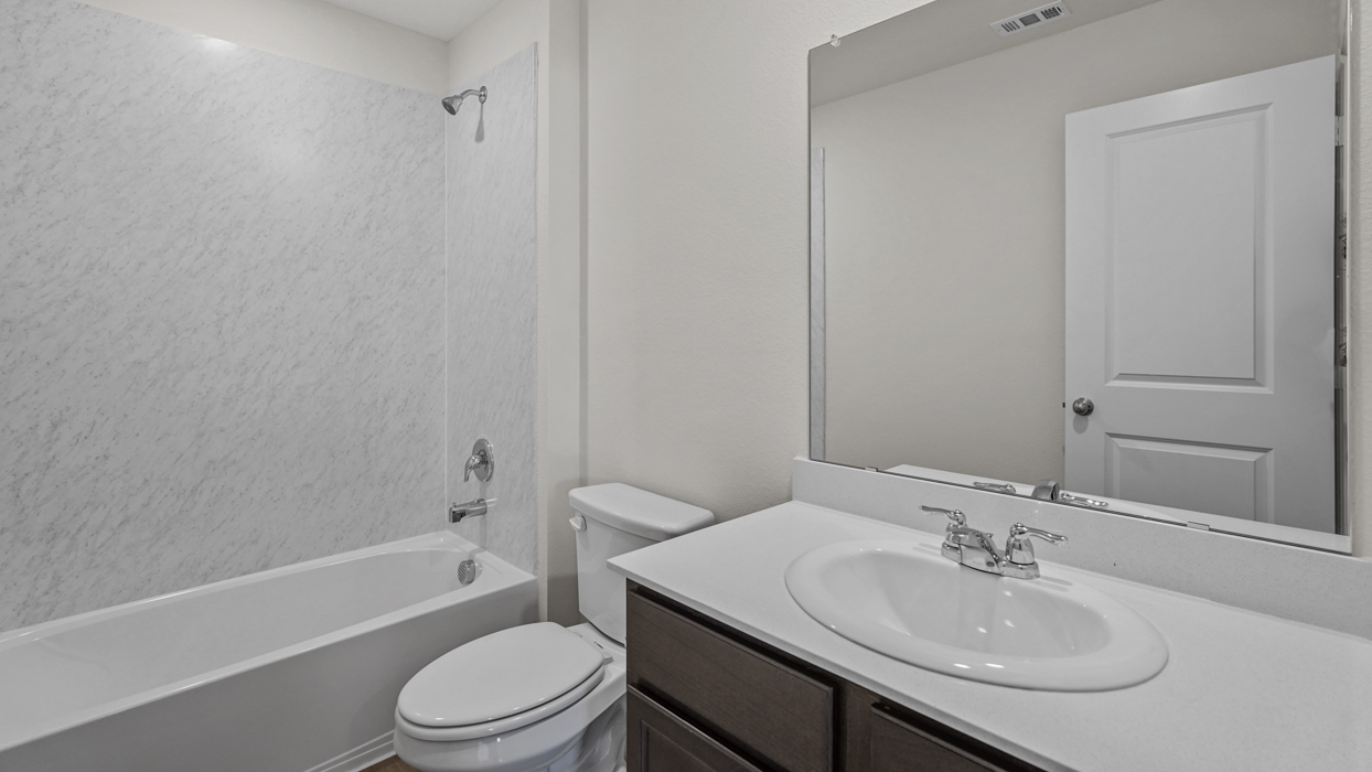 a bathroom with a bath tub shower toilet and sink and dark cabinets