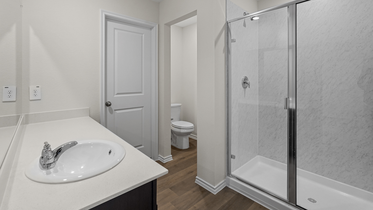 a bathroom with a bath tub shower toilet and sink and dark cabinets