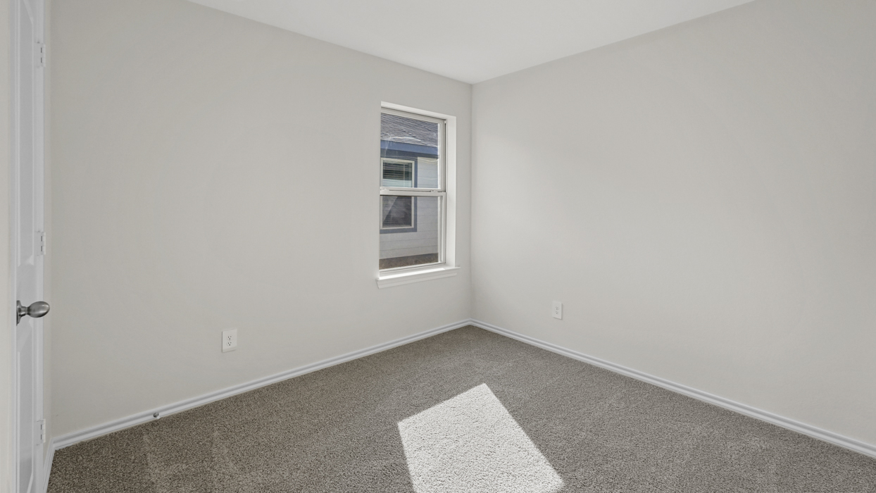 an open bedroom with white walls and gray carpet