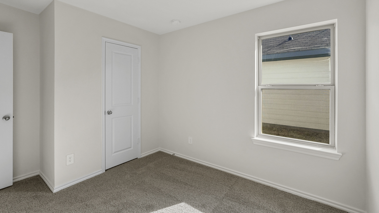 an open bedroom with white walls and gray carpet