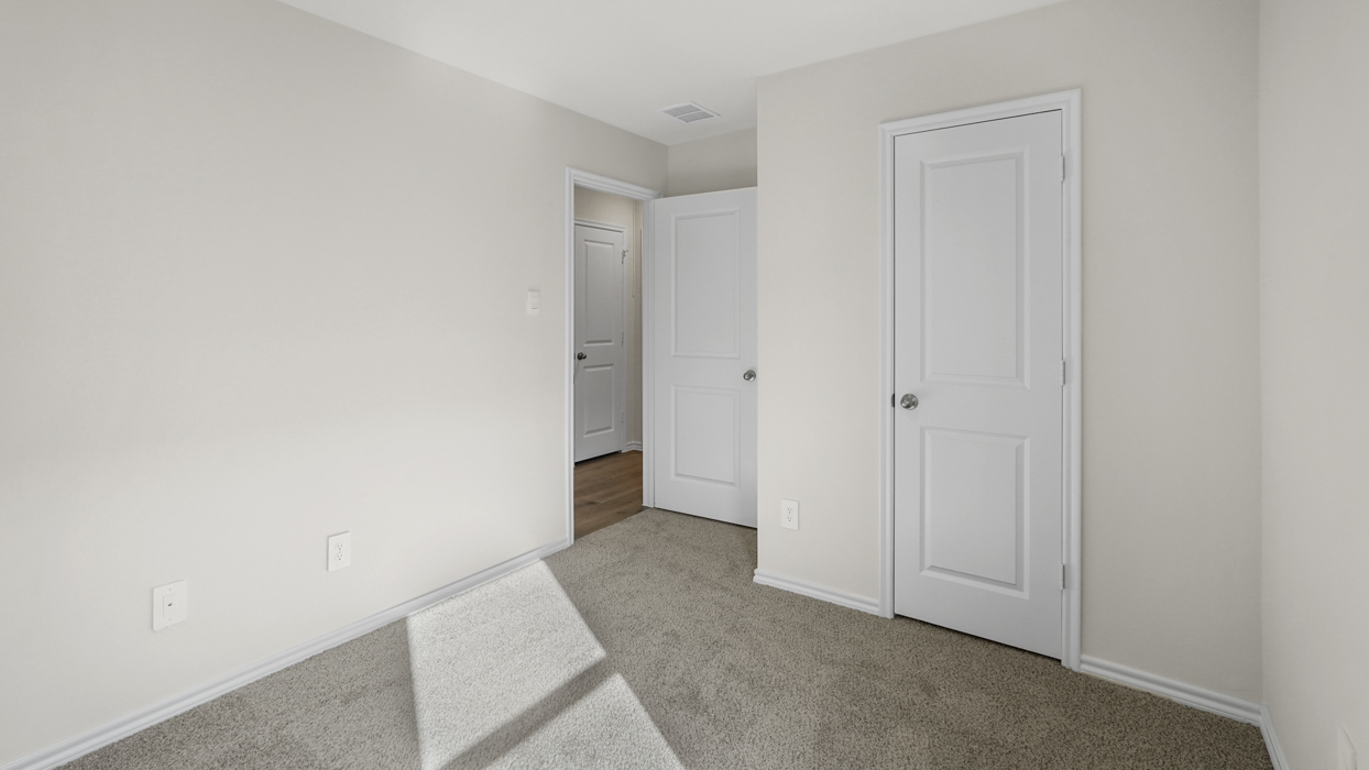 an open bedroom with white walls and gray carpet