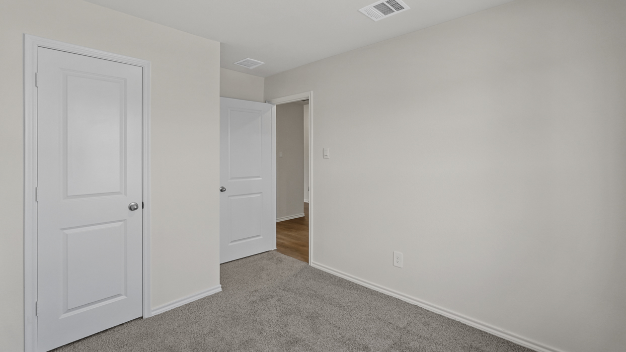 an open bedroom with white walls and gray carpet