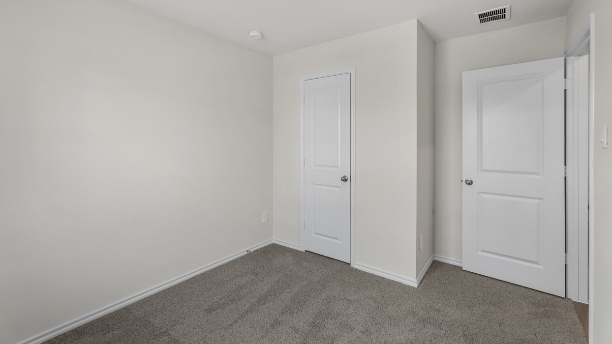 an open bedroom with white walls and gray carpet
