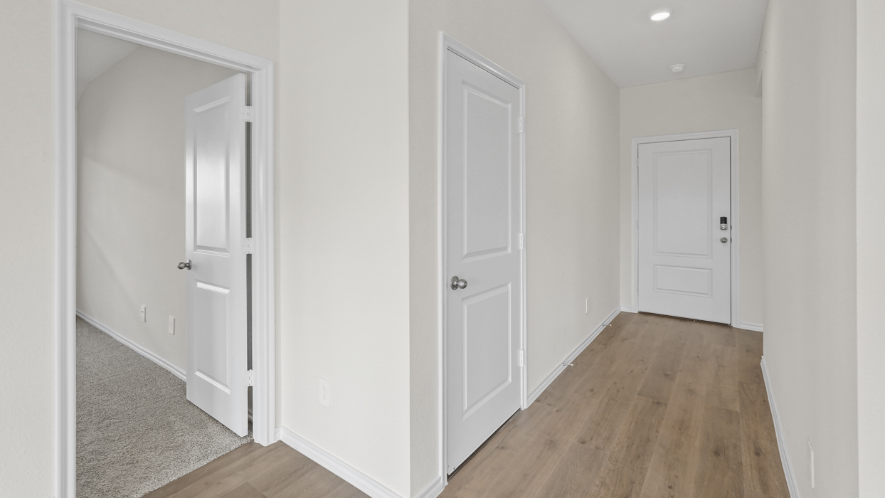 the interior entryway of a home with white walls and wood floors
