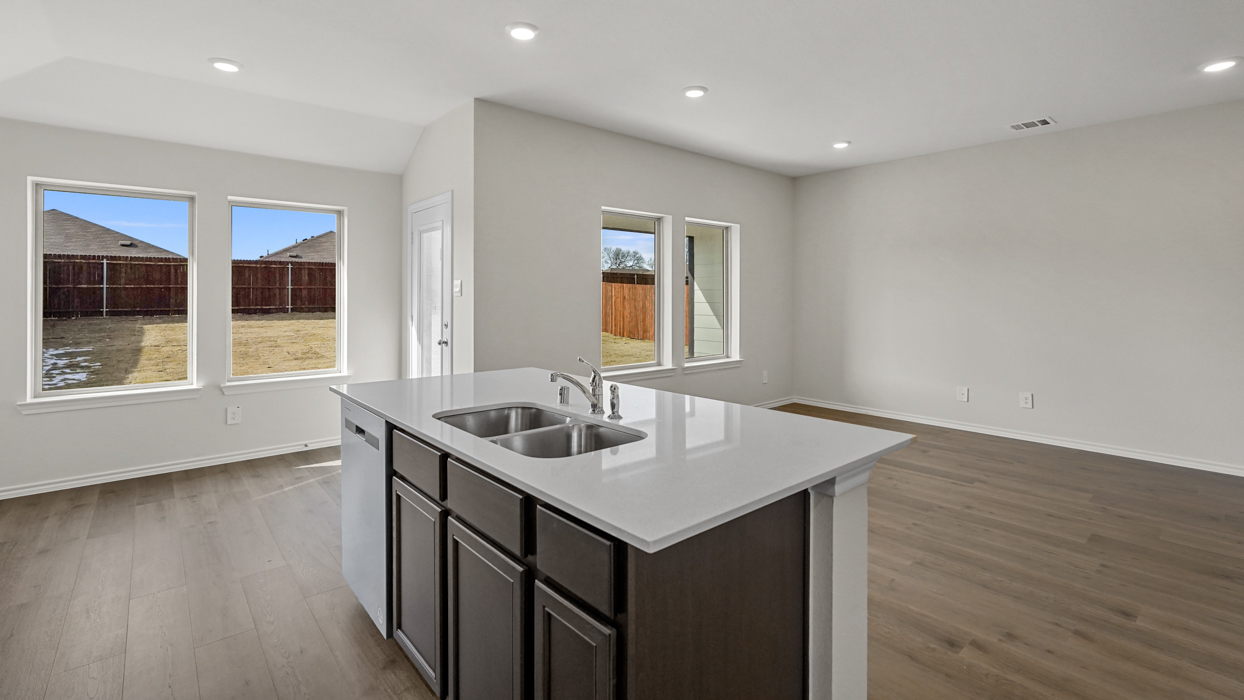 a kitchen with an island in the middle and dark cabinets, white walls and wood floors