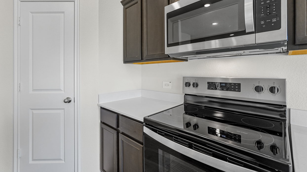 a kitchen with an island in the middle and dark cabinets, white walls and wood floors