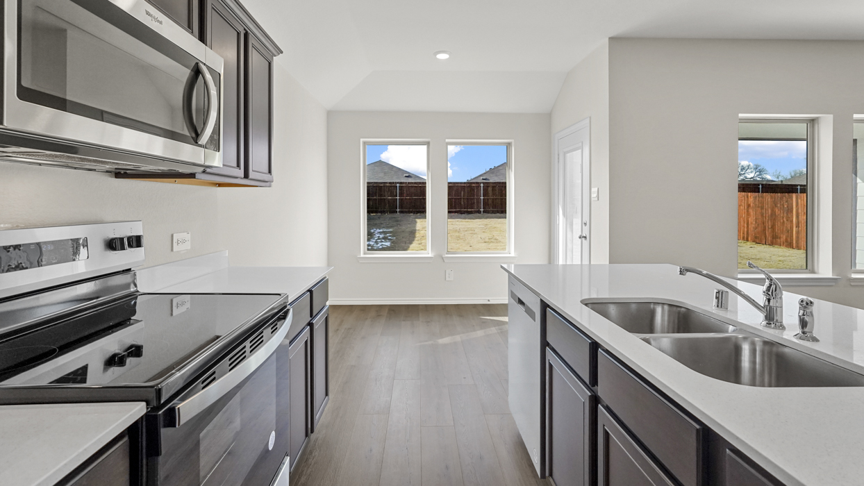 a kitchen with an island in the middle and dark cabinets, white walls and wood floors
