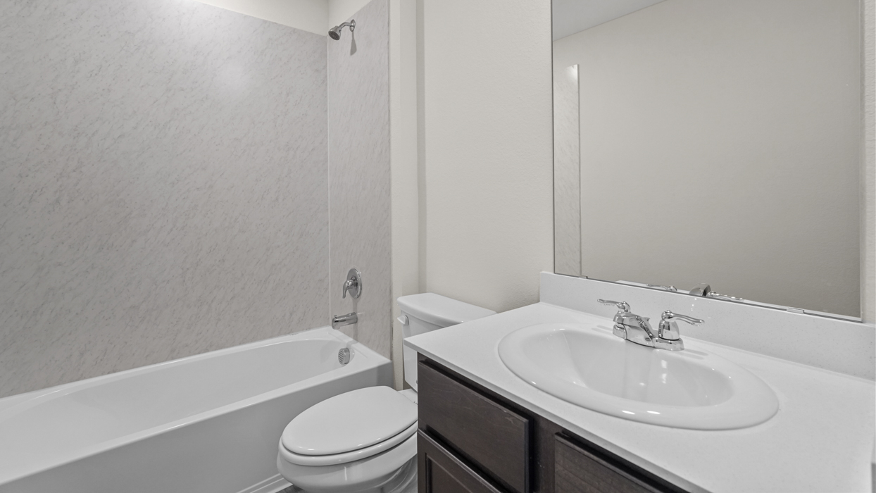 a bathroom with a bath tub a shower a toilet and a sink with dark cabinets