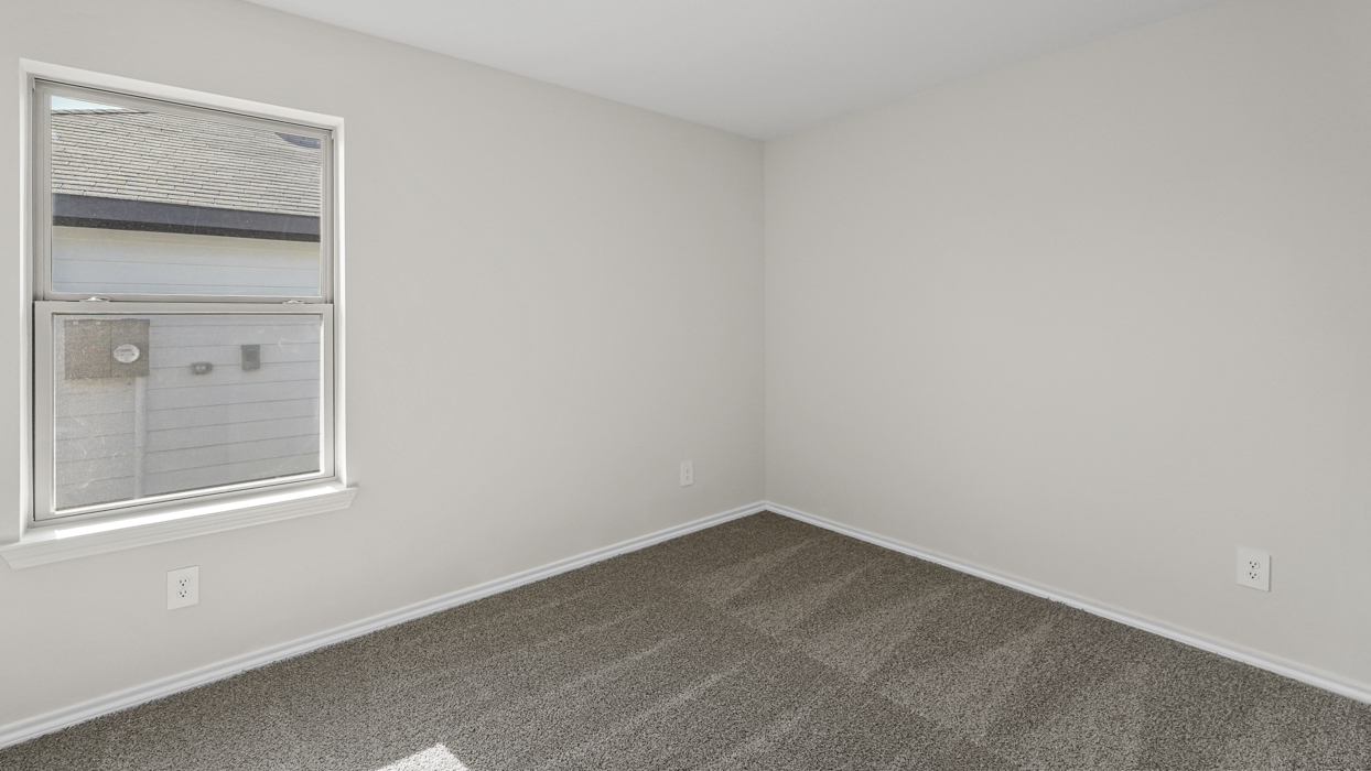 an empty bedroom with windows gray carpet and white walls