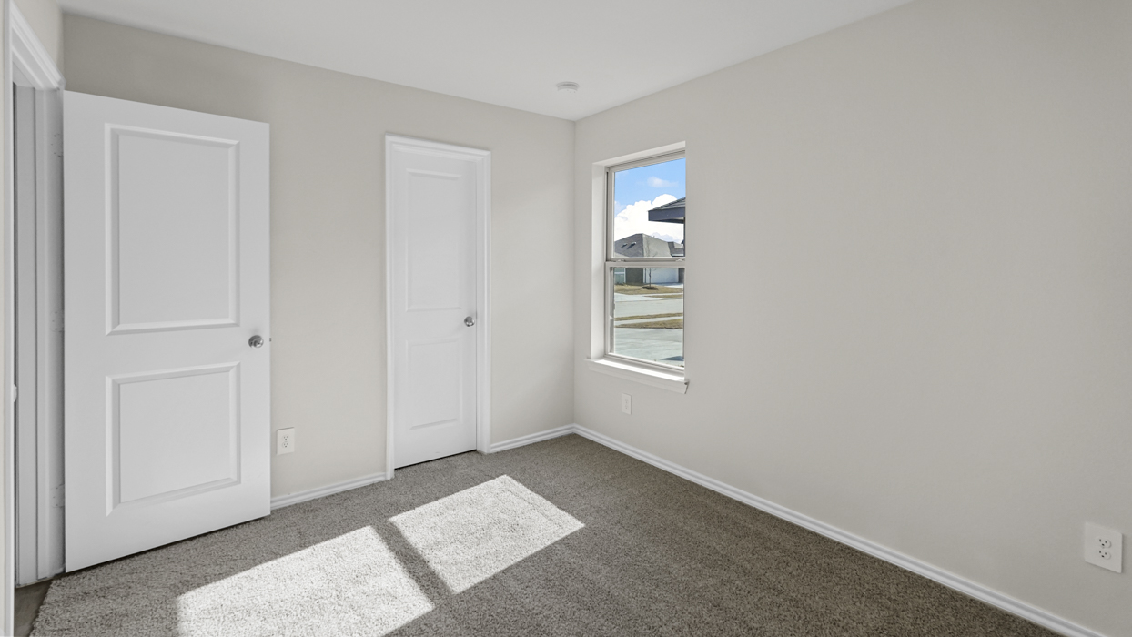 an empty bedroom with windows gray carpet and white walls