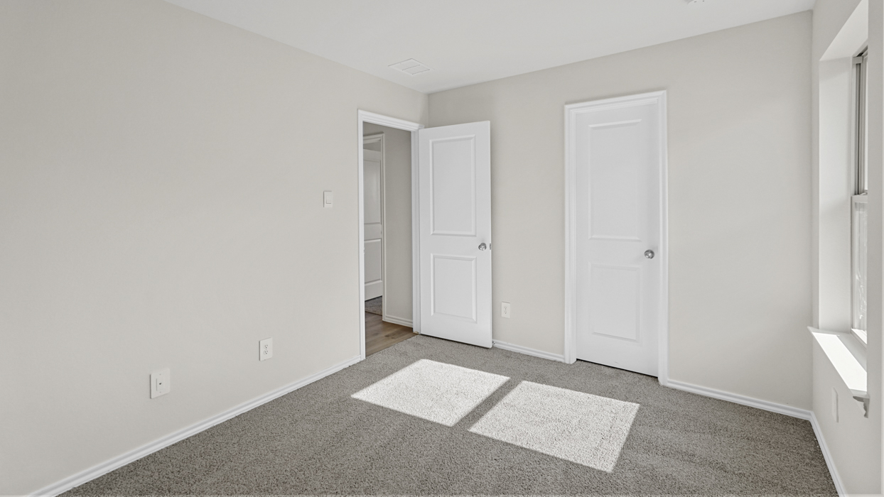 an empty bedroom with windows gray carpet and white walls