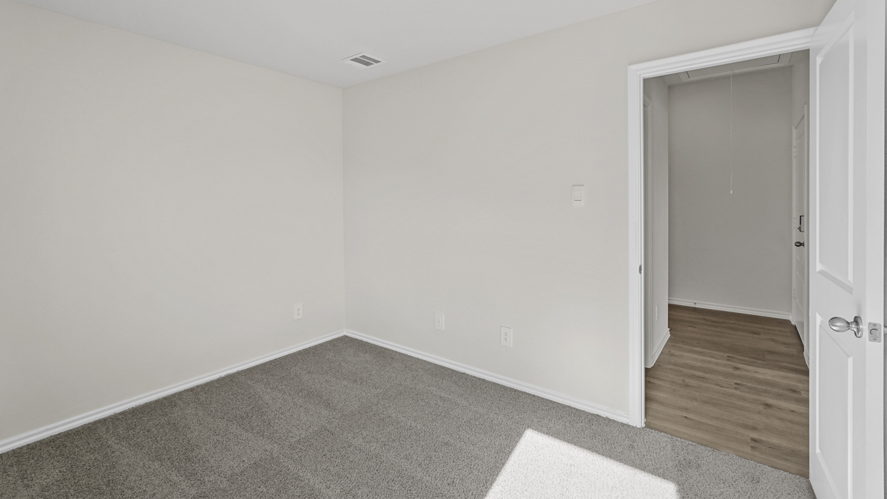 an empty bedroom with windows gray carpet and white walls