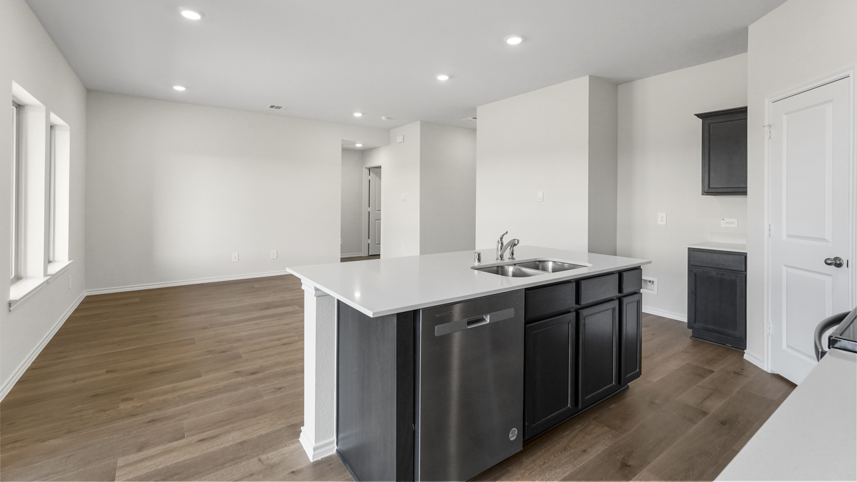 a kitchen with dark cabinets light wood floors an island in the midle and white walls