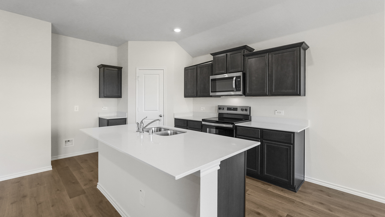 a kitchen with dark cabinets light wood floors an island in the midle and white walls
