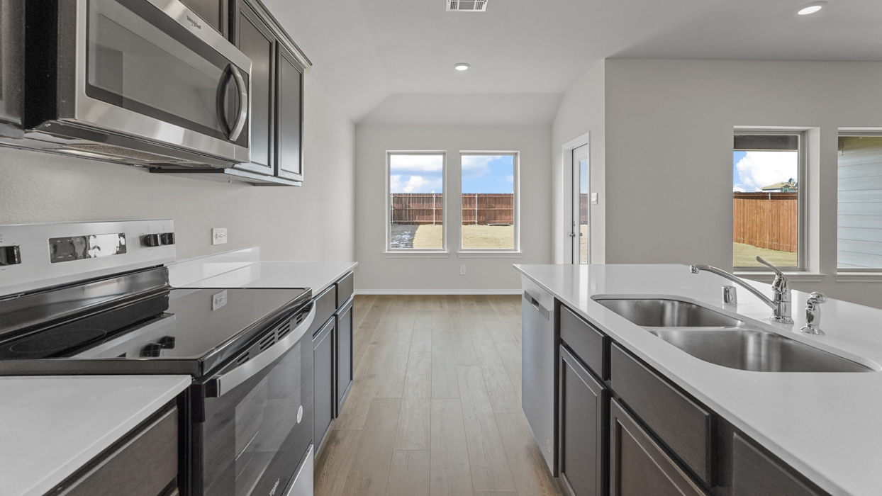 a kitchen with dark cabinets light wood floors an island in the midle and white walls