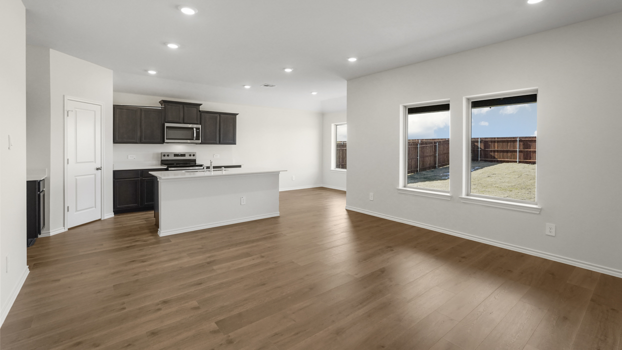 a kitchen with dark cabinets light wood floors an island in the midle and white walls