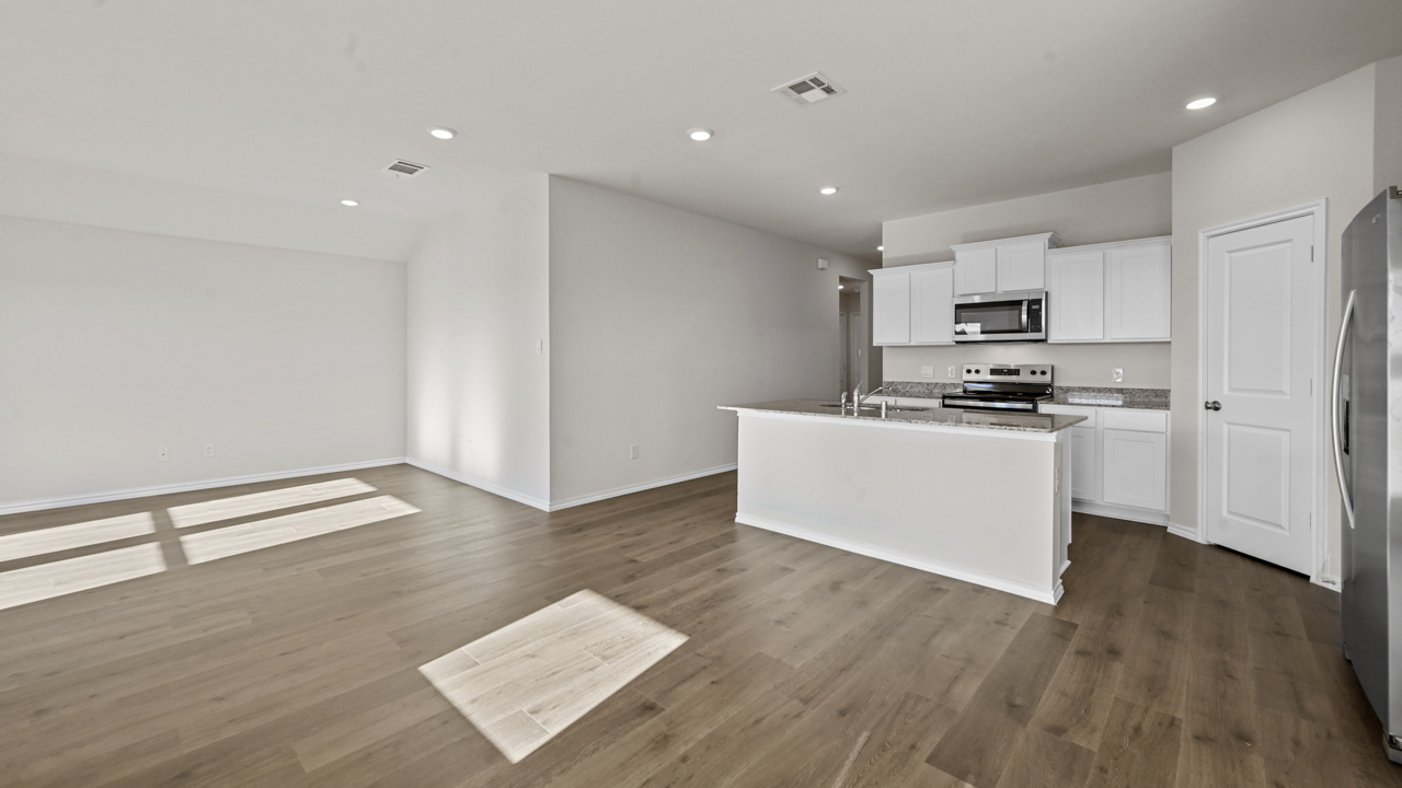 a kitchen with white cabinets and an island in the middle white walls and wood floors