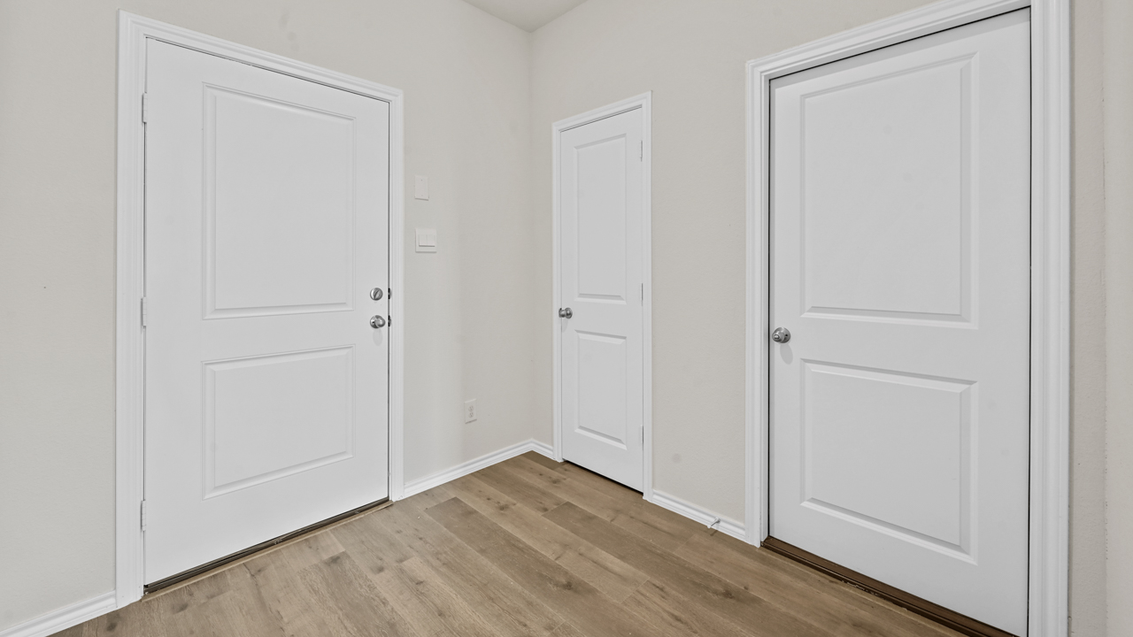 the interior entryway of a home with white walls and wood floors