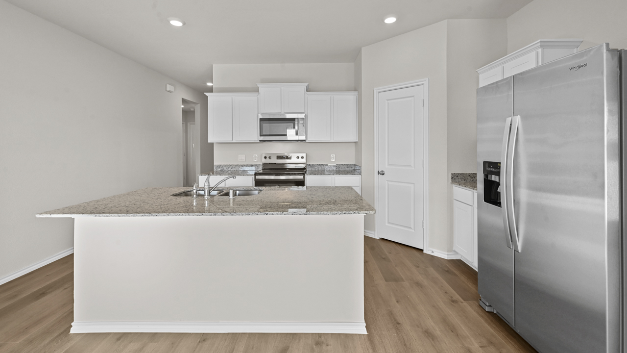 a kitchen with white cabinets and an island in the middle white walls and wood floors