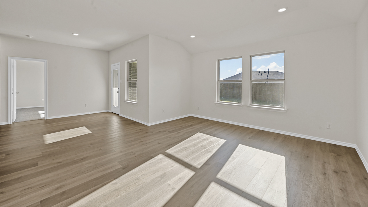 an open living area with wood floors white walls and windows