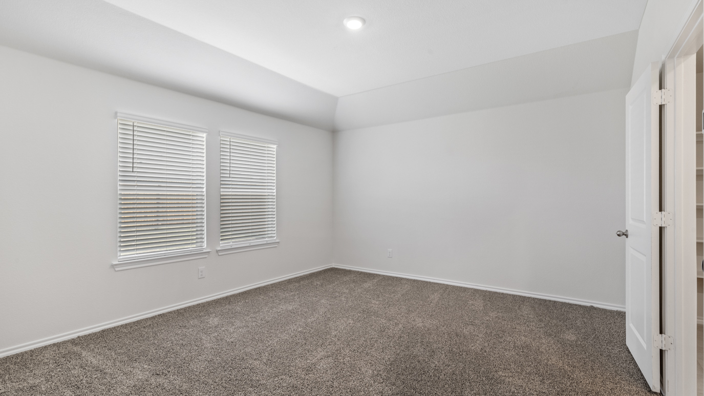 an empty bedroom with gray carpet windows and white walls