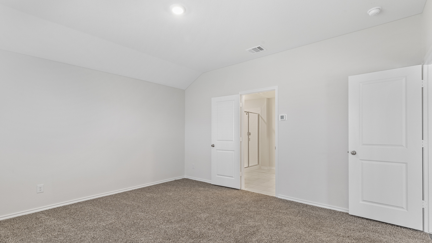 an empty bedroom with gray carpet windows and white walls