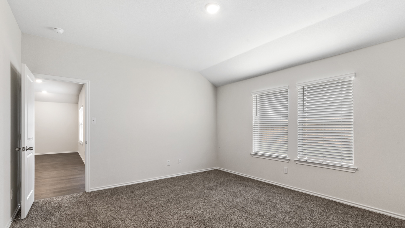 an empty bedroom with gray carpet windows and white walls