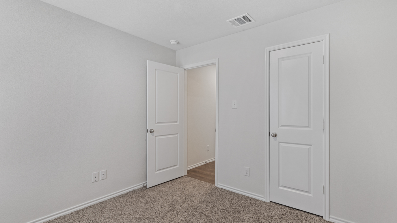 an empty bedroom with gray carpet windows and white walls