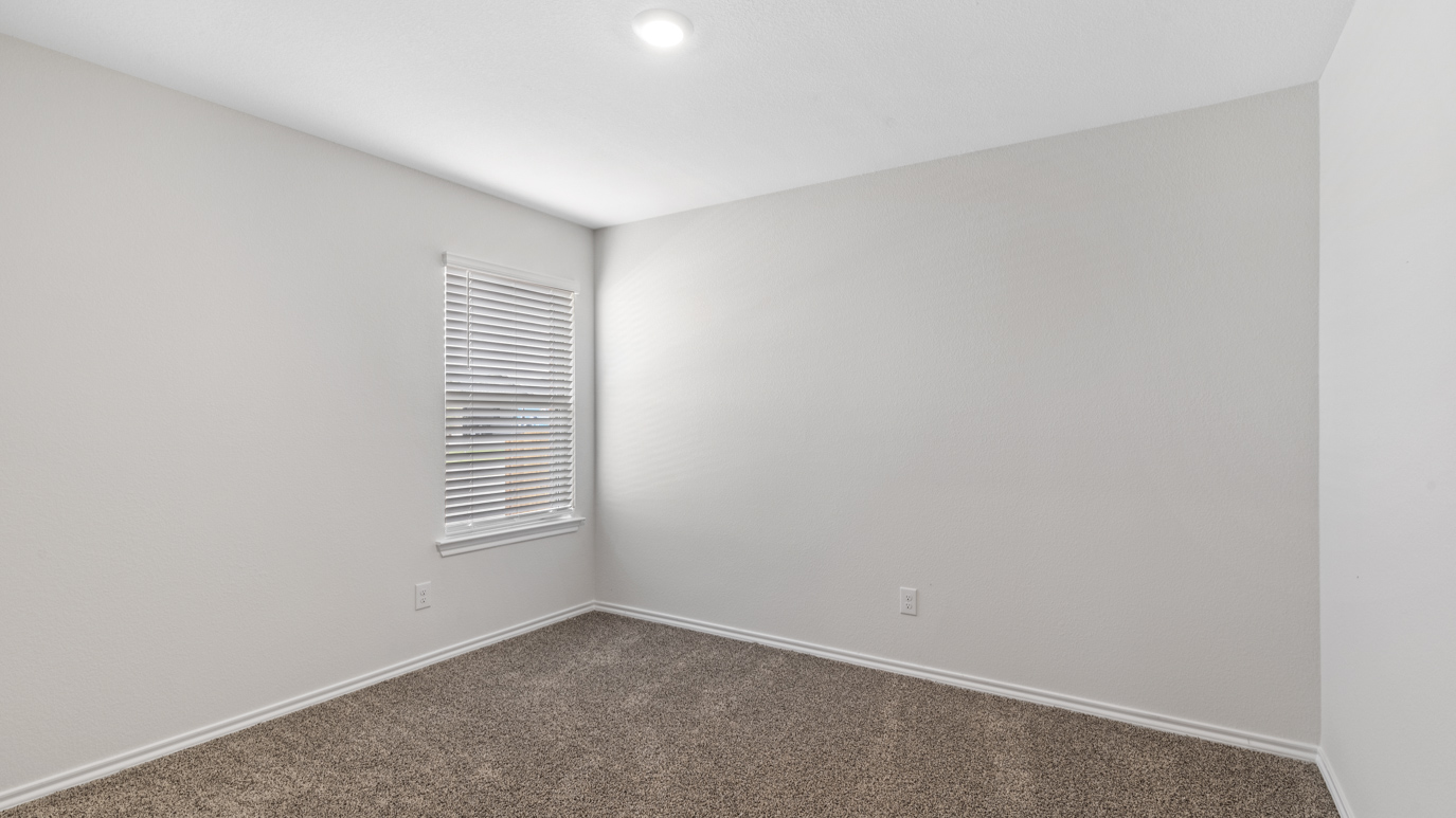 an empty bedroom with gray carpet windows and white walls