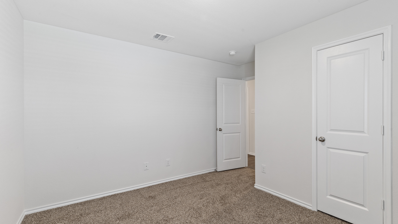 an empty bedroom with gray carpet windows and white walls