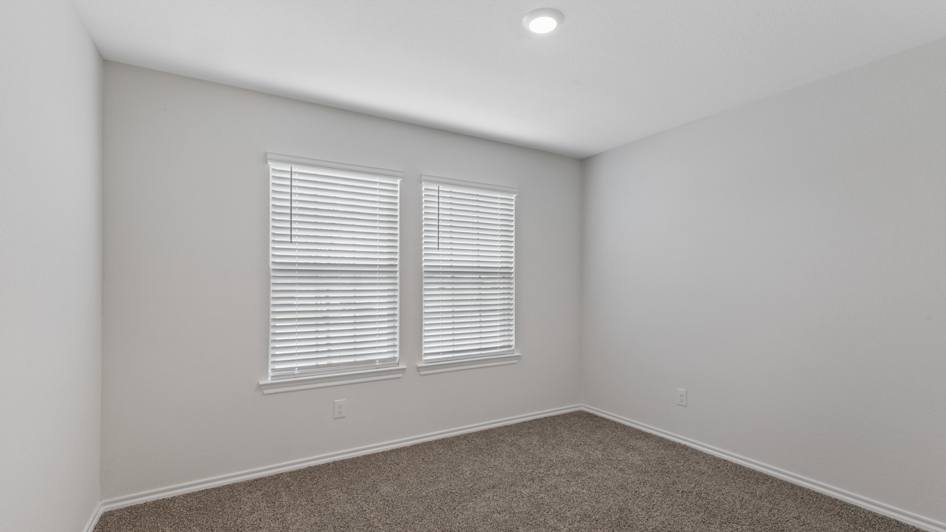 an empty bedroom with gray carpet windows and white walls