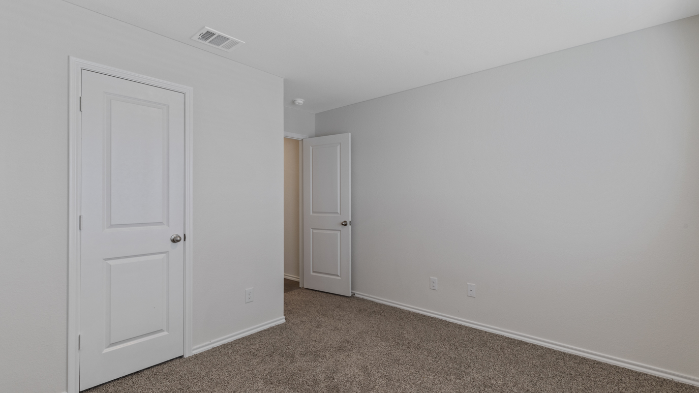 an empty bedroom with gray carpet windows and white walls