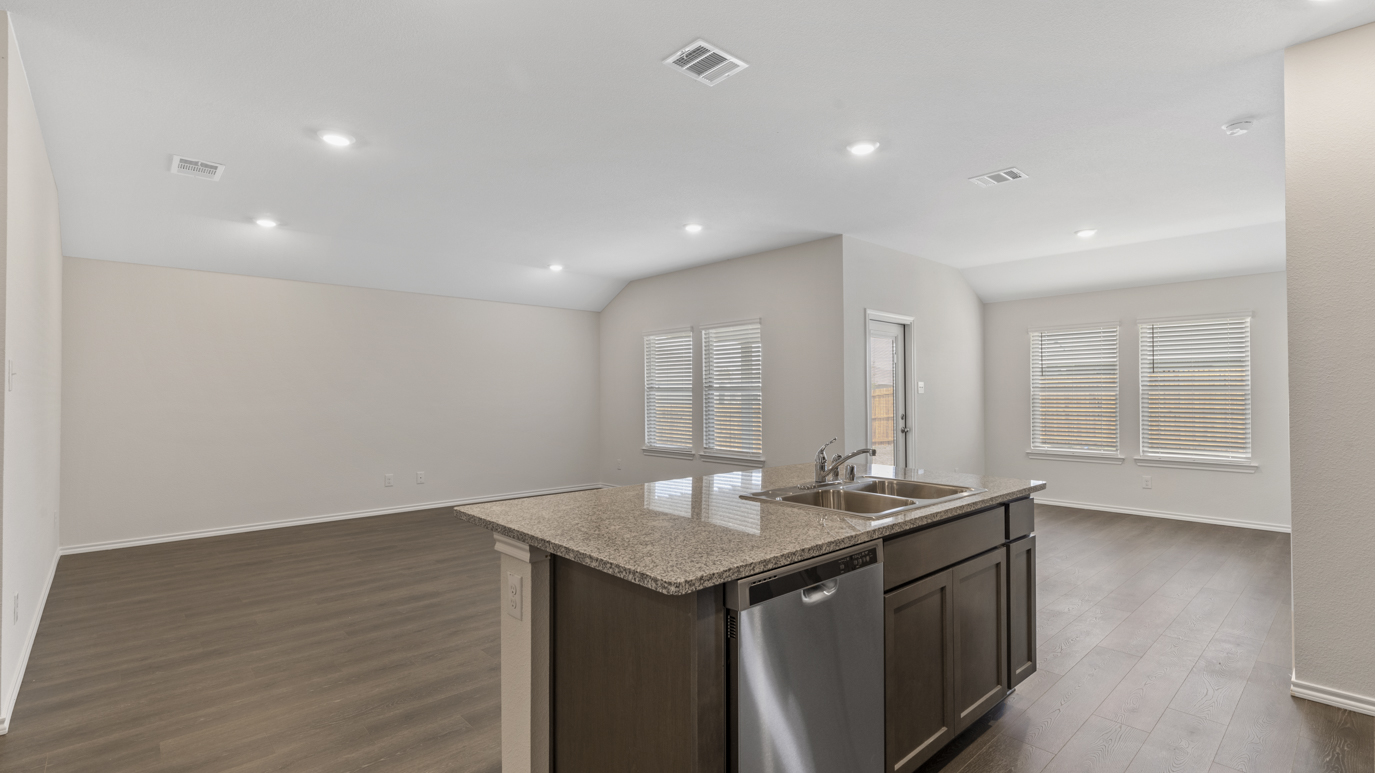 a kitchen with dark cabinets an island in the middle white walls and wood floors
