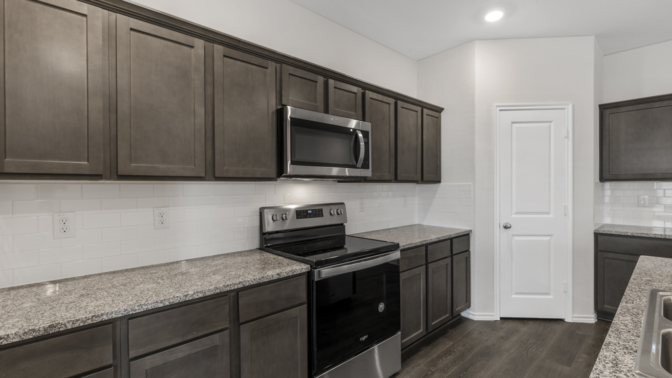 a kitchen with dark cabinets an island in the middle white walls and wood floors